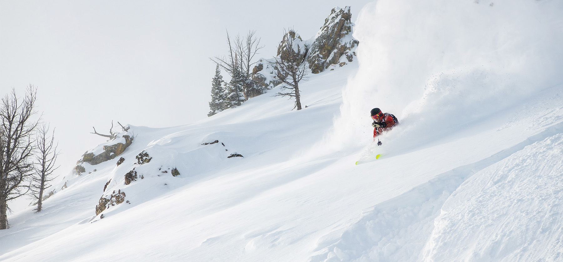 Skier carving through deep powder snow on a steep mountain slope in Jackson Hole, Wyoming